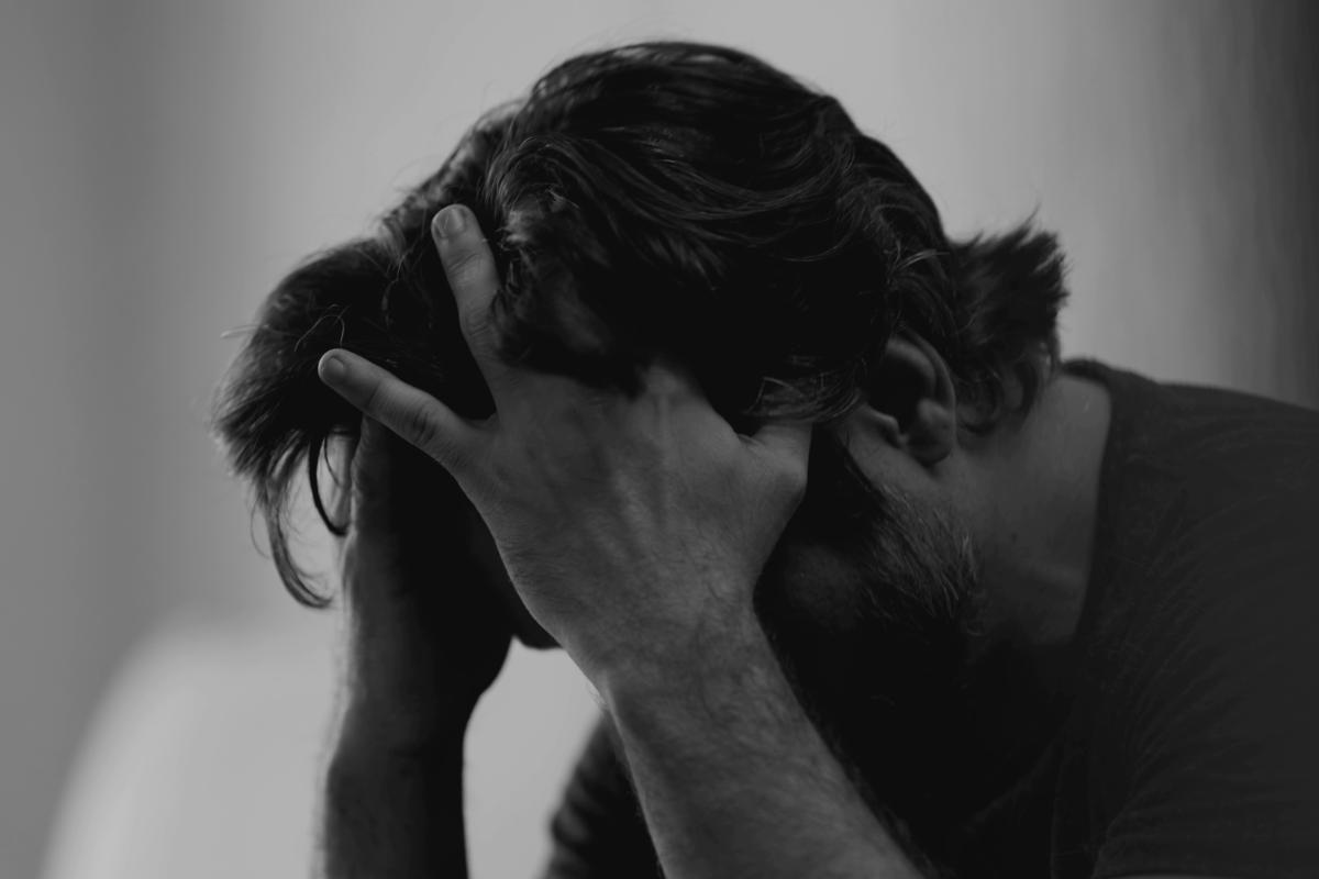 black and white photo of person hanging head while struggling with trauma and addiction