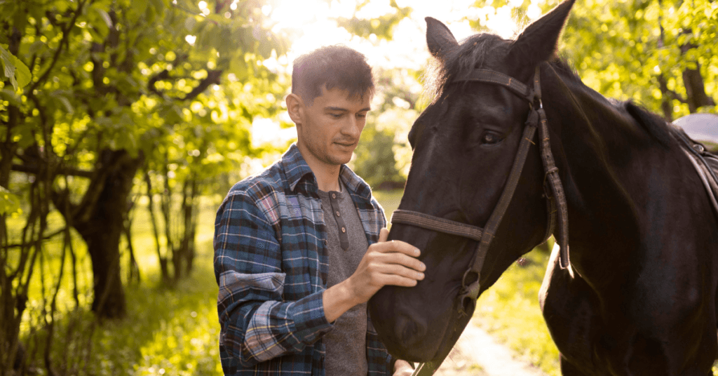 Man interacting with a black horse, learning the benefits of equine therapy for addiction.