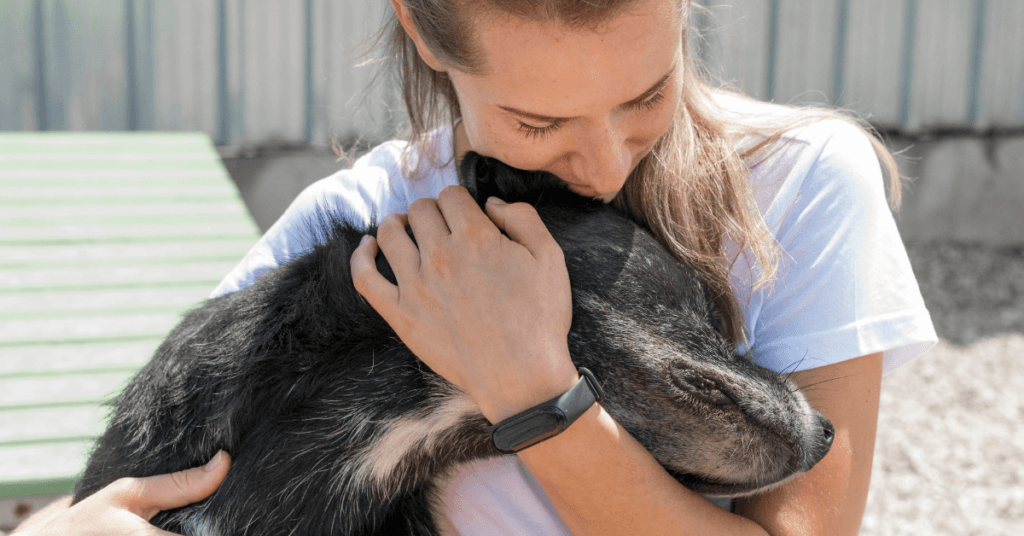 Woman hugging a black dog, learning the benefits of dog friendly rehab.