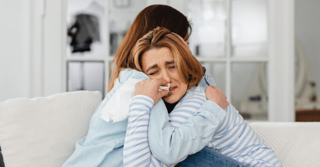 A woman, crying, and hugging her therapist, as they go over her struggles and some coping skills for relapse prevention.
